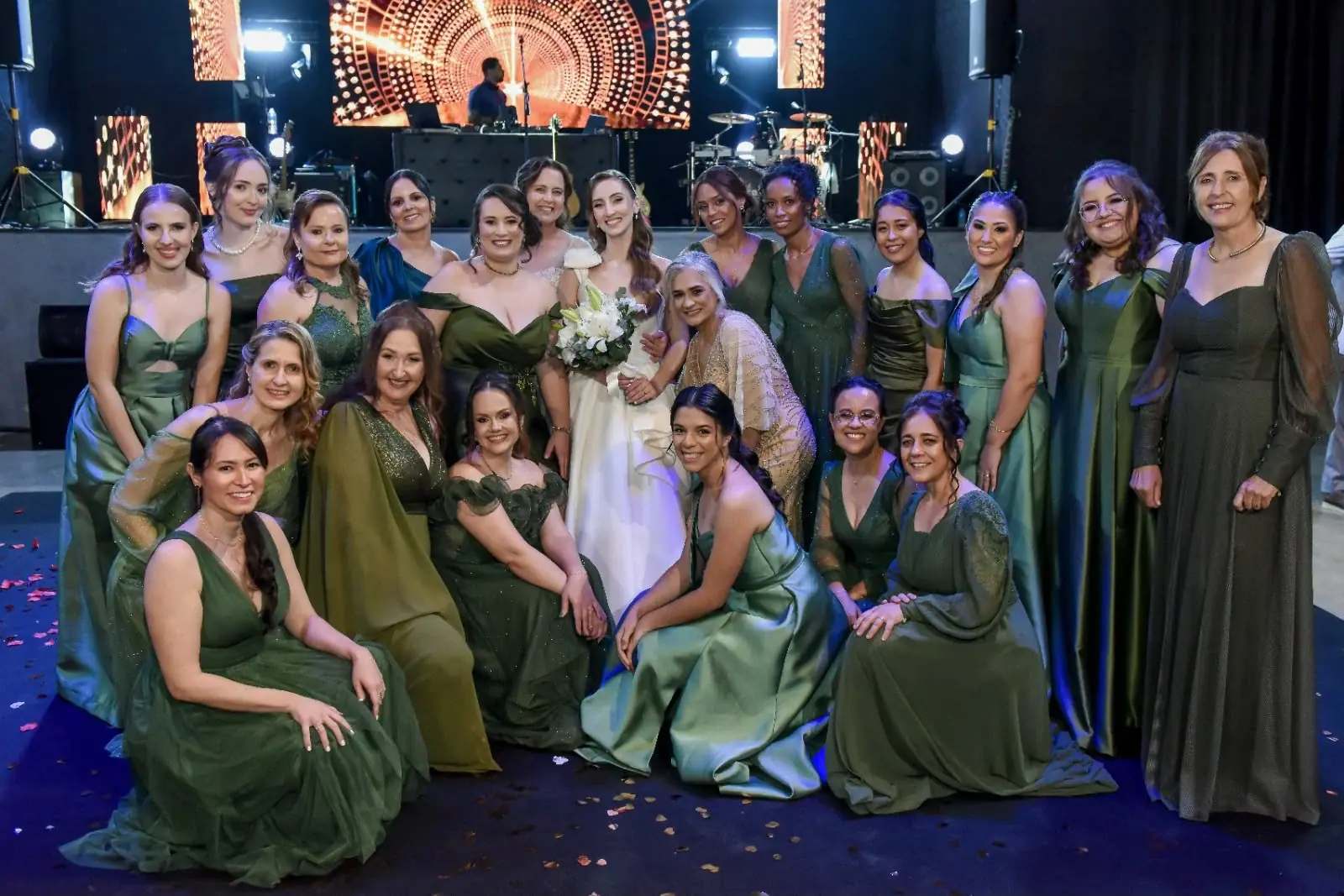 Noiva cercada pelas madrinhas de vestidos verdes na pista.